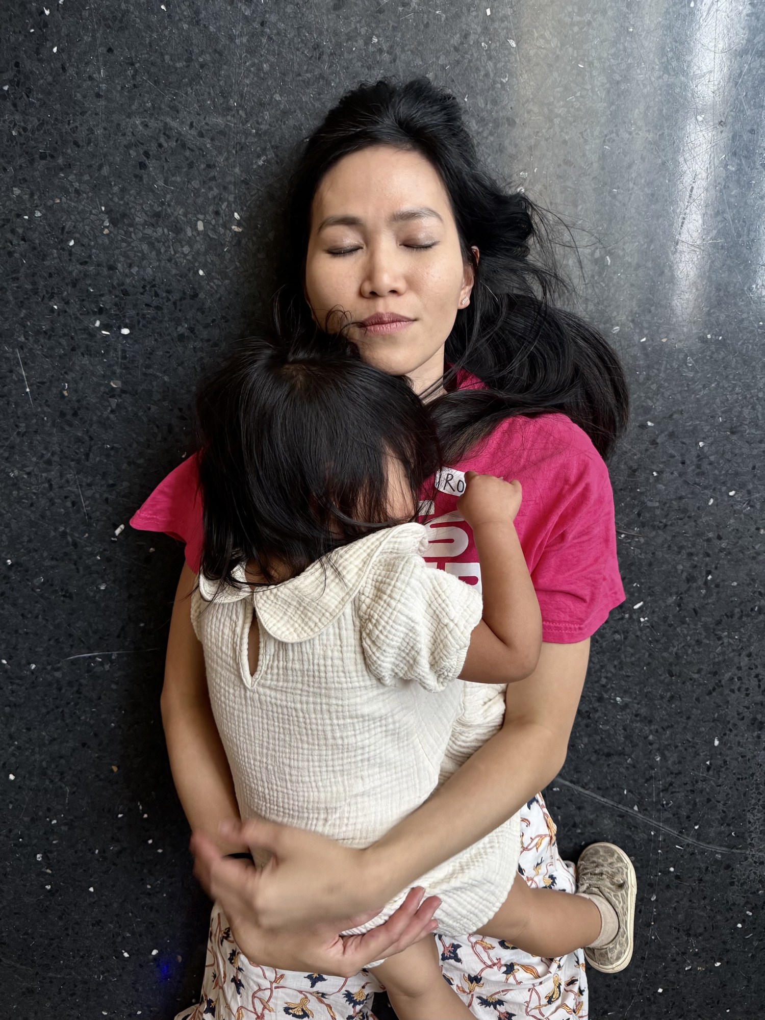 Rong Choy lies on the gallery floor holding her daughter Sabre at the close of the fair.