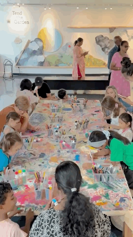 Children and caregivers draw together around the collaborative canvas on Day 3.