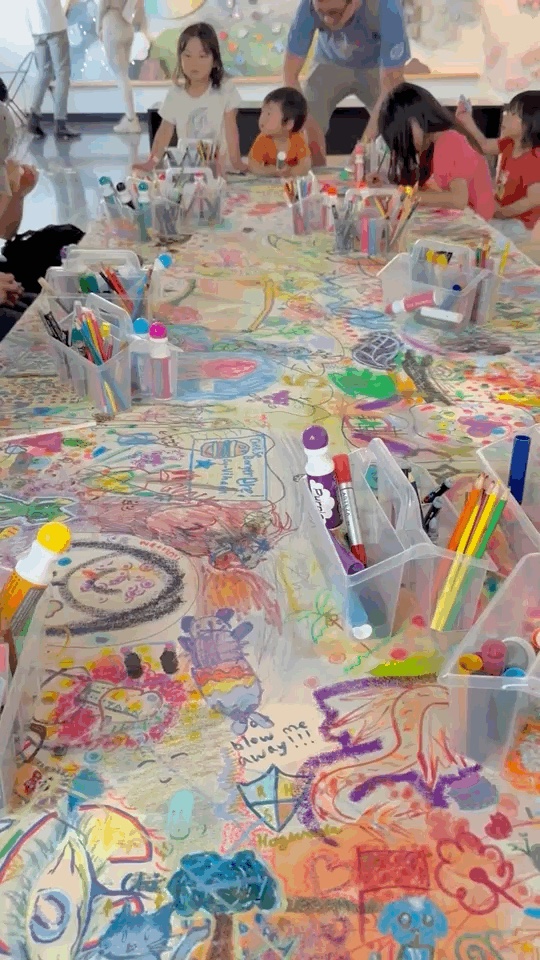 Children draw around the increasingly layered collaborative canvas on Day 2.