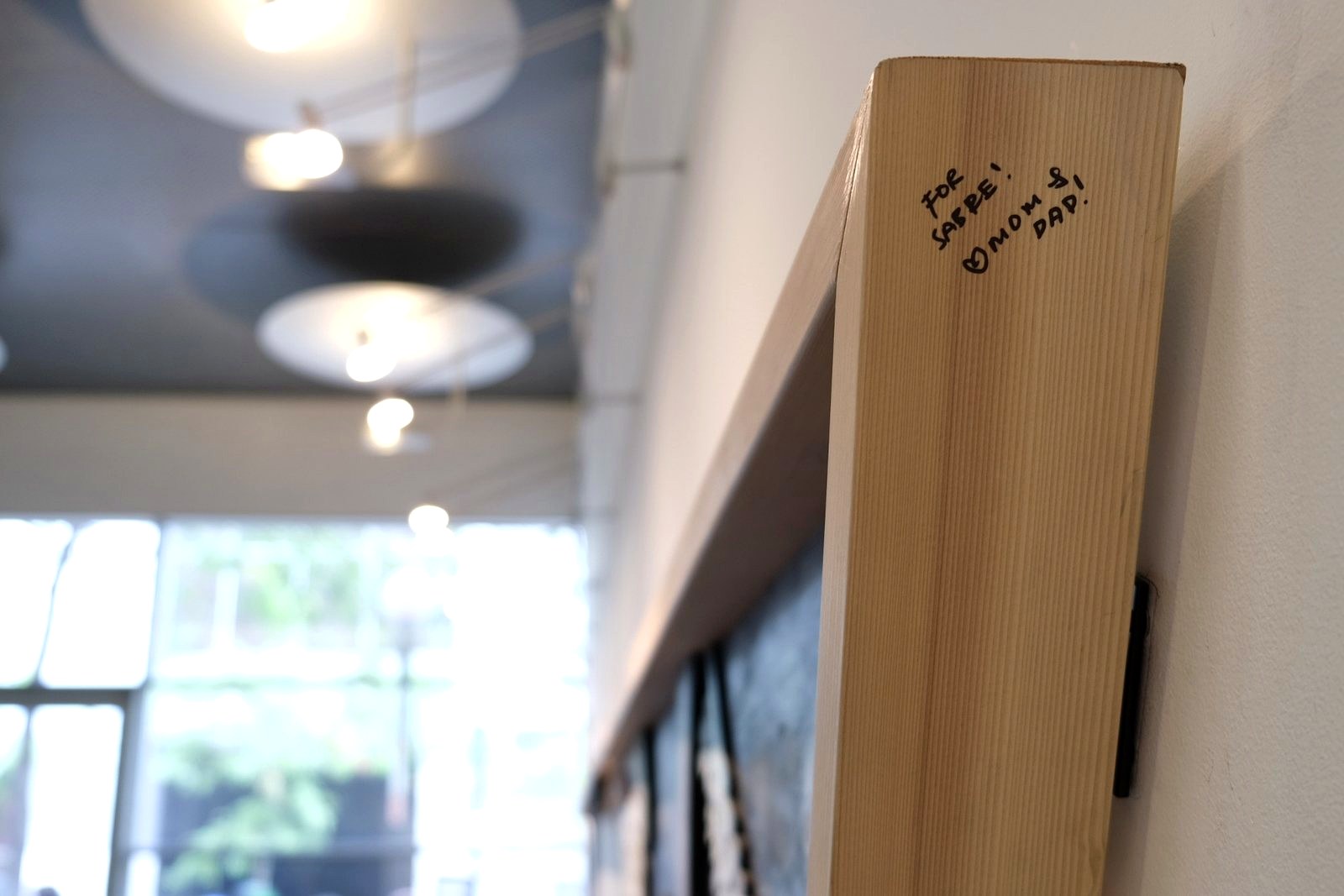The handwritten dedication “For Sabre! Mom & Dad!” on the wooden frame of Tend the Garden.