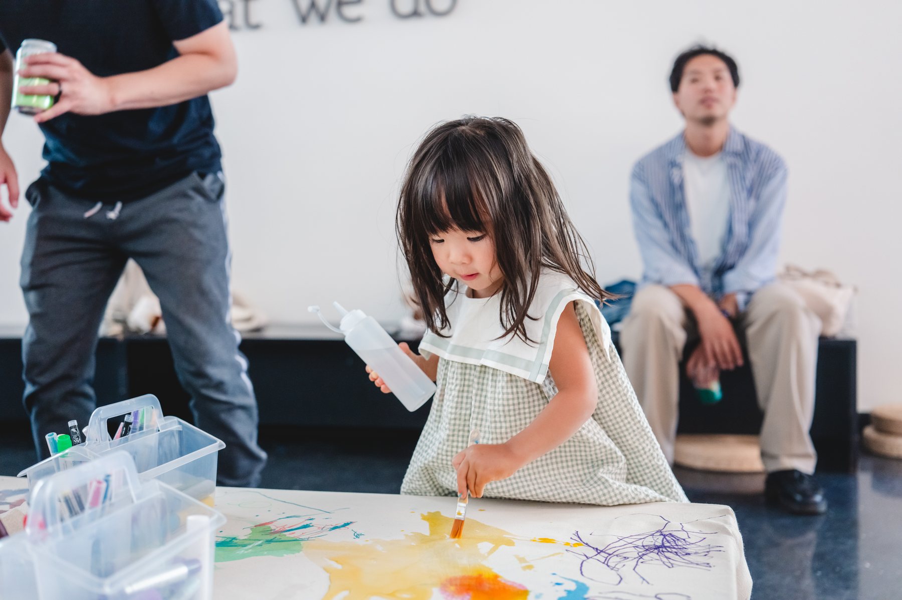 A young child paints a yellow mark on the collaborative canvas during Grow the Garden.